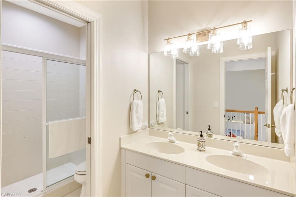 23045 Tree Crest Court Estero, FL 34135 - Photo 27 of 46 Guest Bathroom featuring a private walk-in shower that can be separated from your double vanity by a sliding pocket door