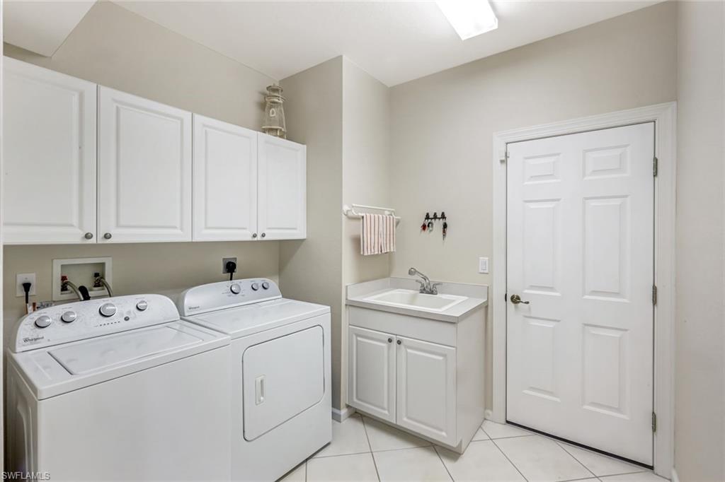 23045 Tree Crest Court Estero, FL 34135 - Photo 29 of 46 Laundry room featuring cabinet space, light tile patterned floors, and a full-sized utility sink