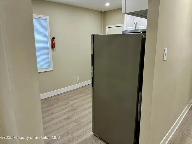 a view of a refrigerator in kitchen and an empty room