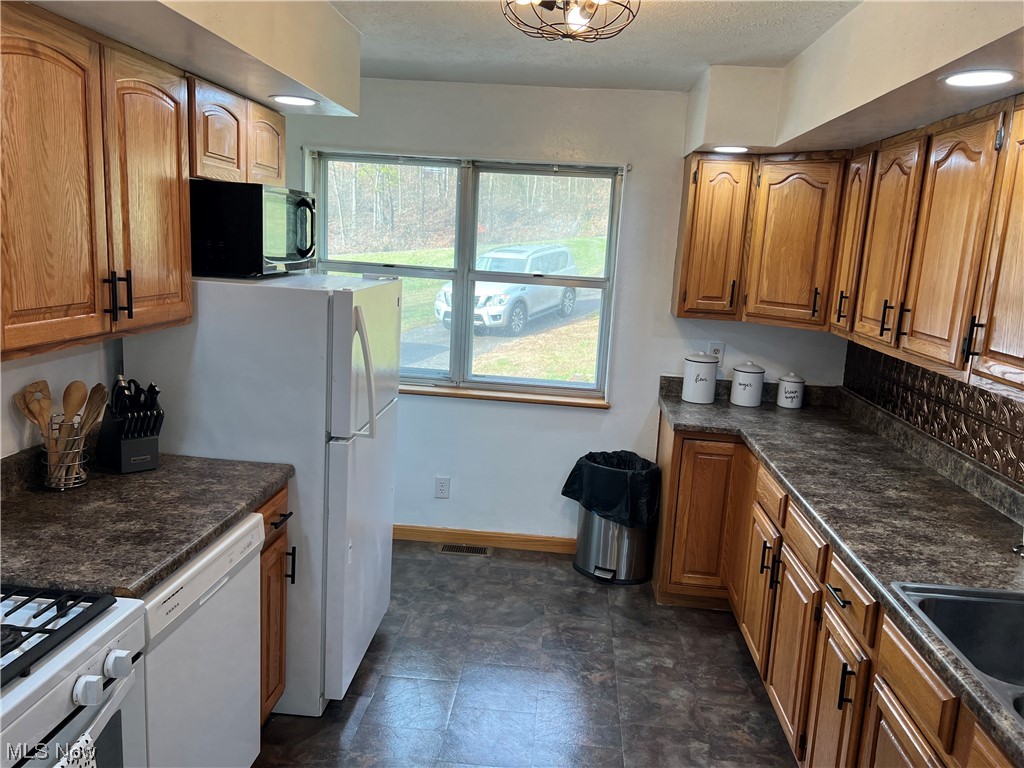 6950 Walker Road Walker, WV 26180 - Photo 4 of 22 Kitchen with white dishwasher, dark tile flooring, a healthy amount of sunlight, and sink