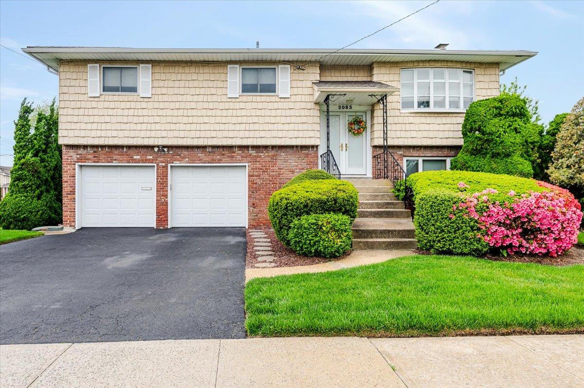 Split foyer home featuring asphalt driveway, a garage, and brick siding