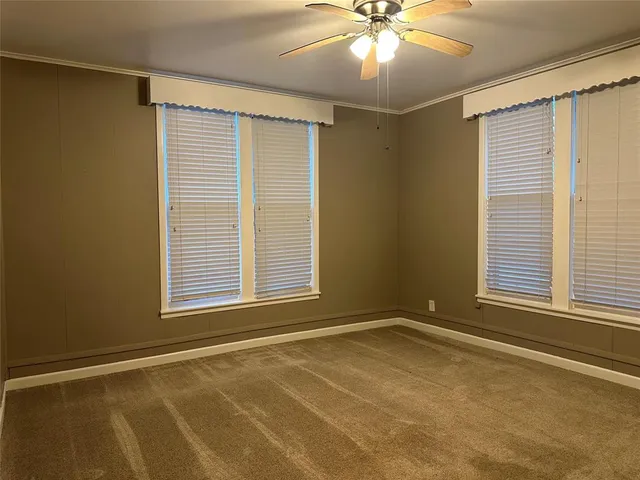 an empty room with windows and fan