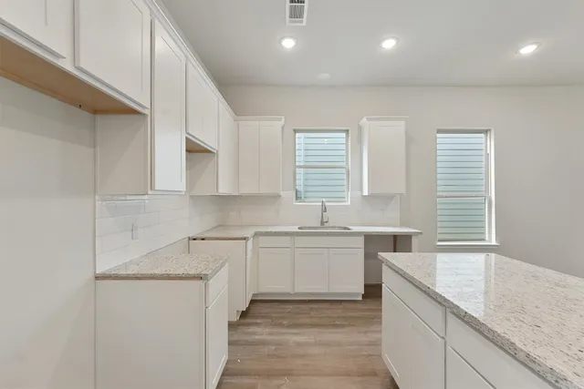 a large white kitchen with stainless steel appliances granite countertop a sink and dishwasher with white cabinets