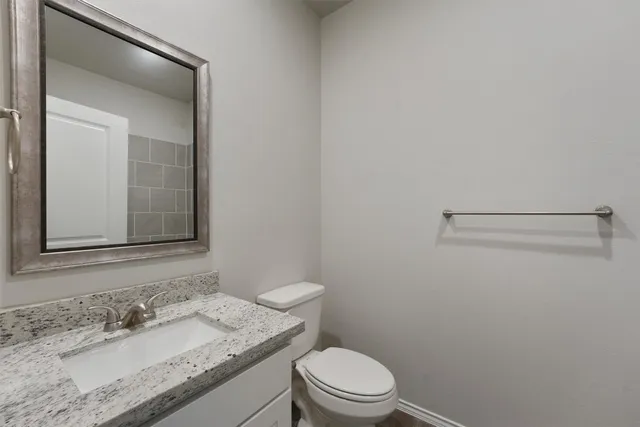 a bathroom with a granite countertop sink toilet and mirror