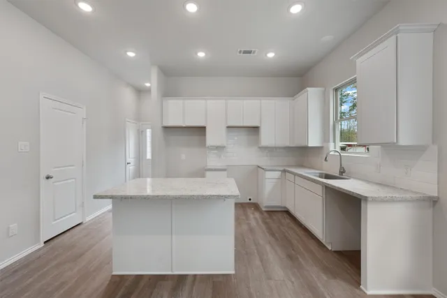 a kitchen with kitchen island sink stove and cabinets