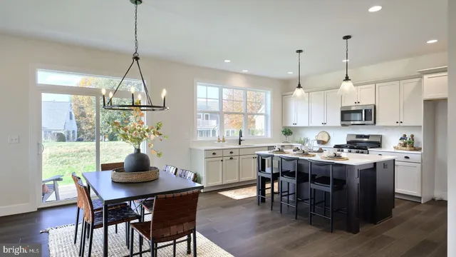 a kitchen with stainless steel appliances a dining table chairs stove and white cabinets