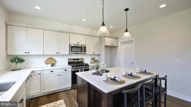 a kitchen with stainless steel appliances kitchen island granite countertop a sink a stove a microwave a counter space and cabinets