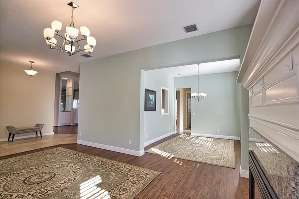 a view of a hallway with wooden floor and a chandelier