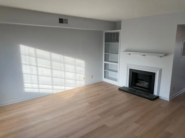 an empty room with windows and fireplace