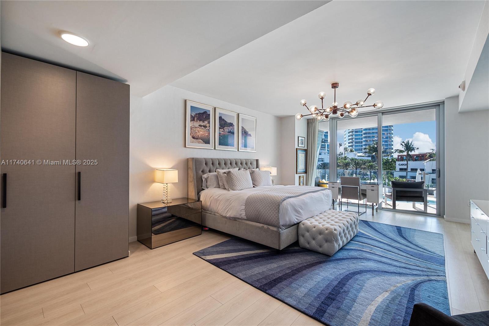 1 Collins Avenue, Unit 304 Miami Beach, FL 33139 - Photo 14 of 40 a spacious bedroom with a bed a chandelier and couch