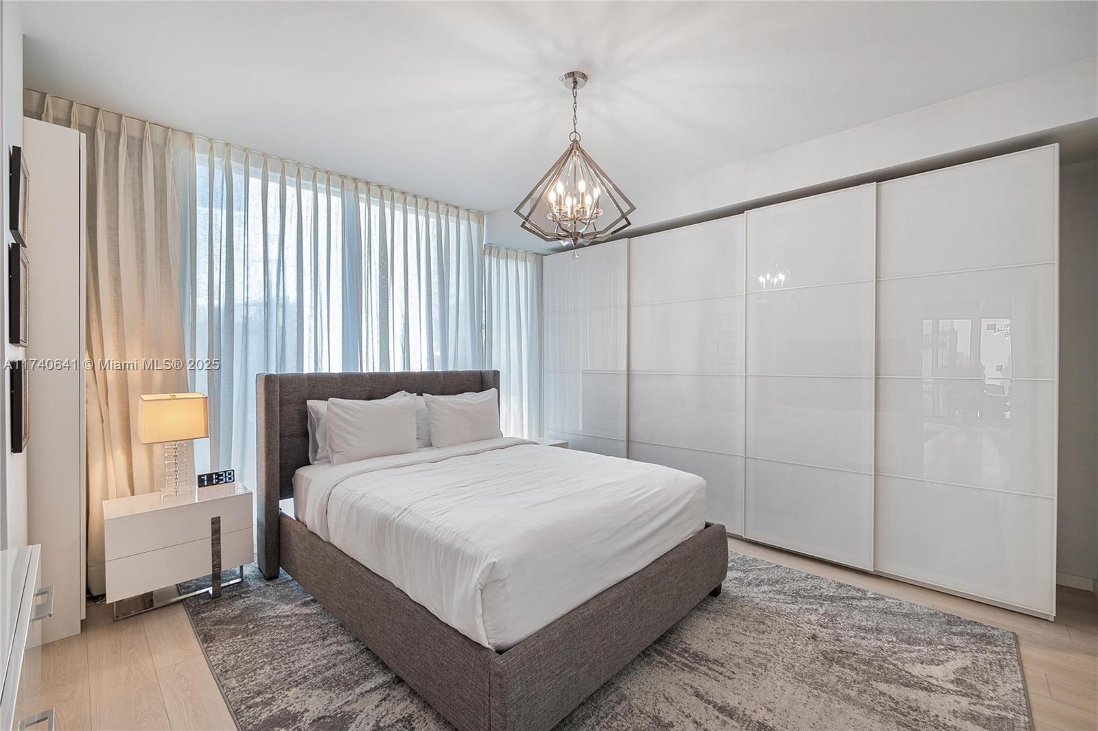 1 Collins Avenue, Unit 304 Miami Beach, FL 33139 - Photo 23 of 40 a bedroom with a large bed and a chandelier