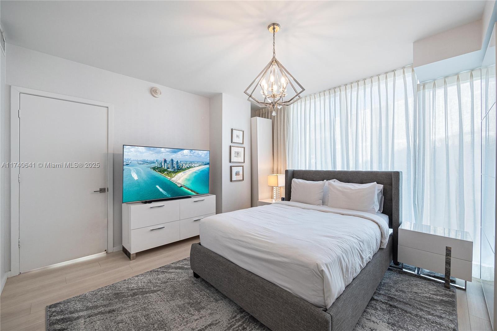 1 Collins Avenue, Unit 304 Miami Beach, FL 33139 - Photo 24 of 40 a bedroom with bed and a chandelier