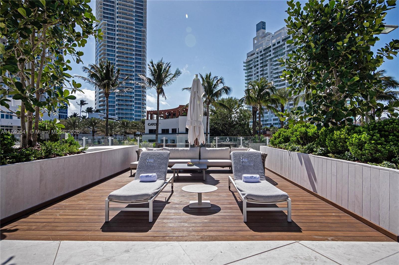 1 Collins Avenue, Unit 304 Miami Beach, FL 33139 - Photo 32 of 40 a view of a patio with couches and a table and chairs with wooden floor and fence