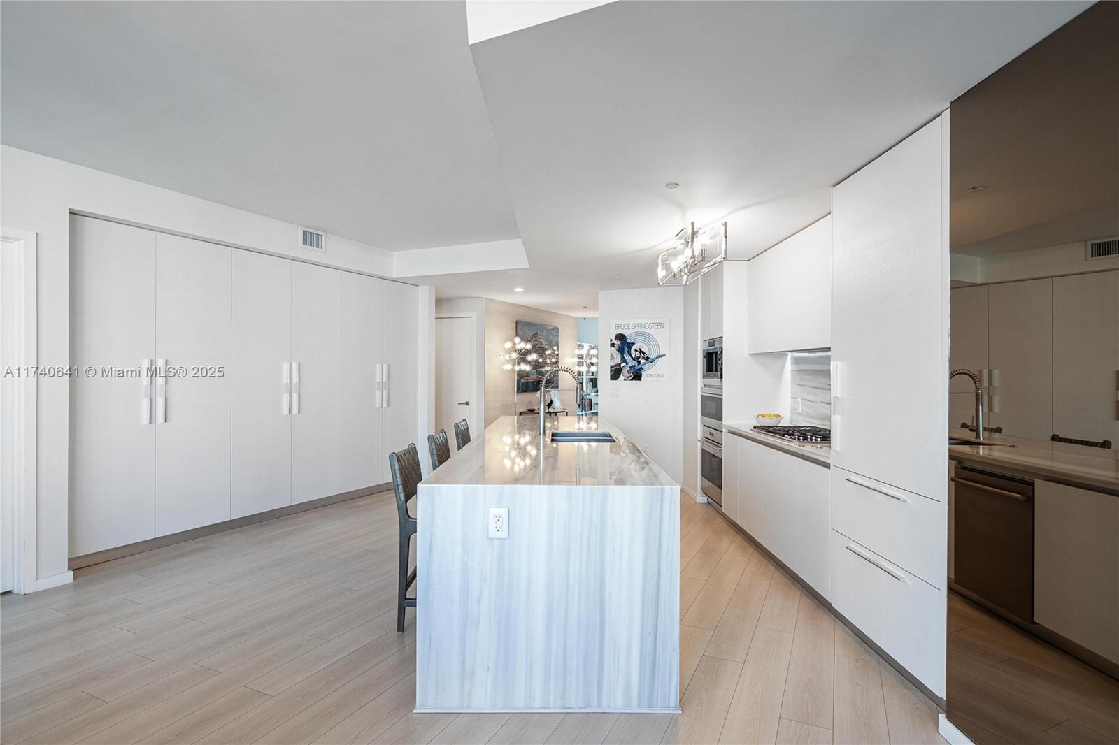 1 Collins Avenue, Unit 304 Miami Beach, FL 33139 - Photo 10 of 40 a view of a kitchen with a sink dishwasher stove and refrigerator with wooden floor