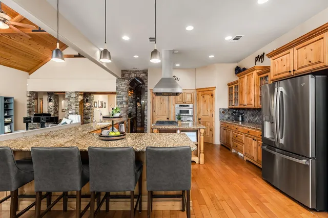a kitchen with stainless steel appliances granite countertop a table chairs and a refrigerator