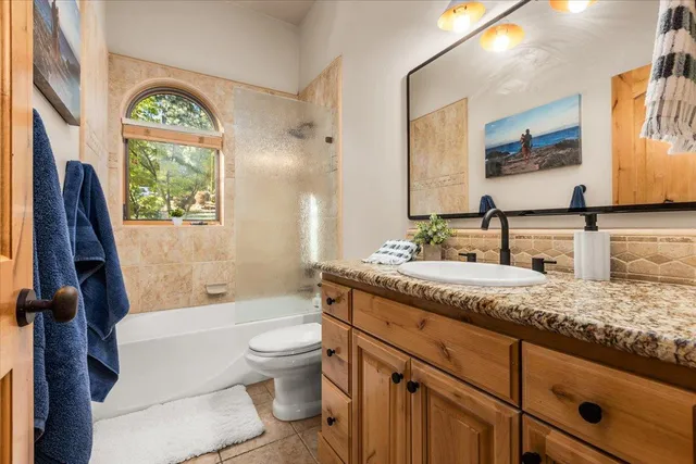 a bathroom with a granite countertop toilet a sink a mirror a bathtub and next to a window