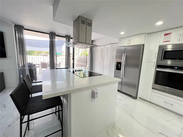 a kitchen with stainless steel appliances a stove a refrigerator a sink a dining table and chairs
