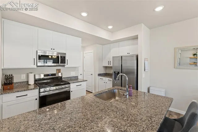 a kitchen with stainless steel appliances granite countertop a stove refrigerator sink and cabinets