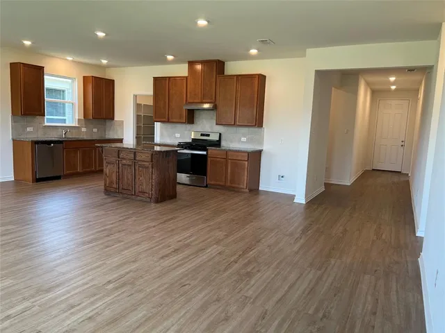 a kitchen with stainless steel appliances kitchen island granite countertop wooden floors and a sink