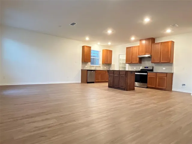 a view of kitchen with stainless steel appliances granite countertop a stove top oven a sink and dishwasher with wooden floor