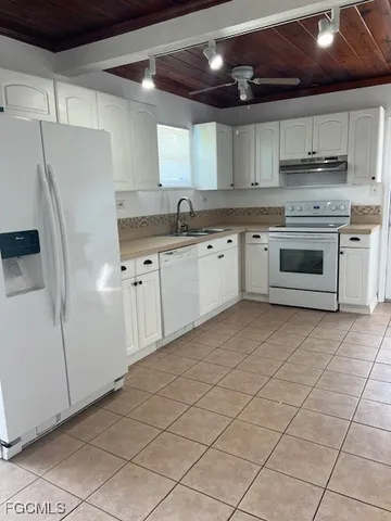 a kitchen with granite countertop a refrigerator sink and cabinets