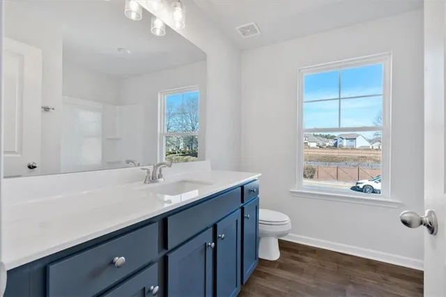a bathroom with a granite countertop sink a toilet a window and mirror