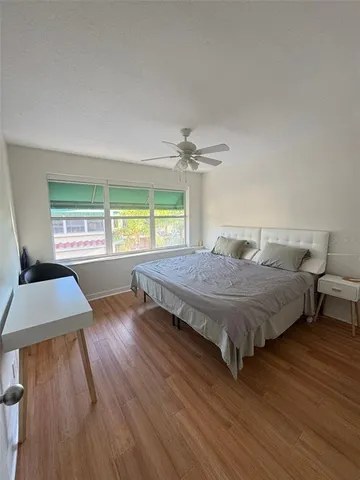 a bedroom with a bed window and wooden floor