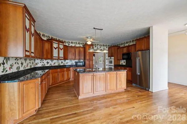 a kitchen with stainless steel appliances granite countertop a refrigerator and a stove top oven