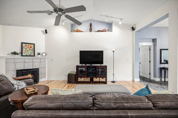 a room with stainless steel appliances kitchen island granite countertop wooden floors and a view of living room