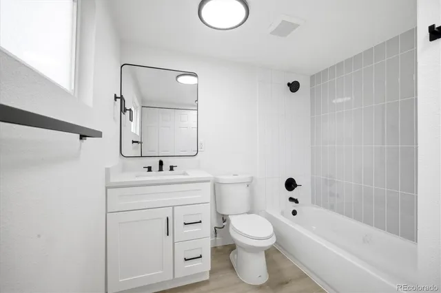 a bathroom with a toilet sink vanity tub and mirror