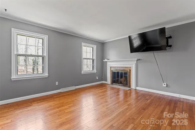 a view of empty room with wooden floor fireplace and windows