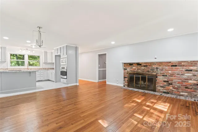 an empty room with fireplace wooden floor and windows