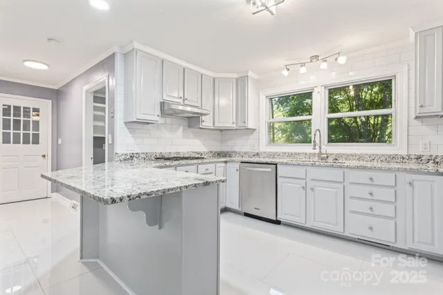 a kitchen with granite countertop white cabinets and a large window