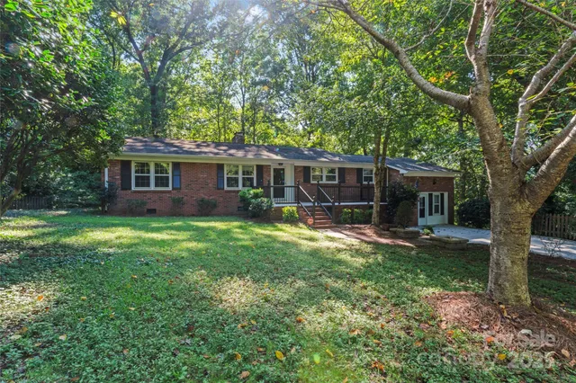 a view of a house with a yard and a large tree