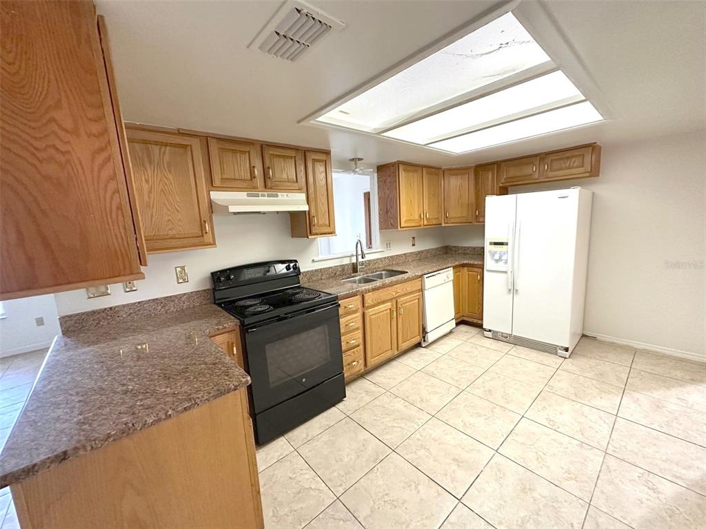 5061 Barnegat Point Road Orlando, FL 32808 - Photo 9 of 33 a kitchen with stainless steel appliances granite countertop a stove a sink and a refrigerator