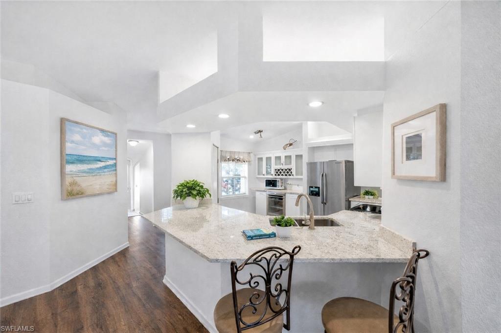 10801 Halfmoon Shoal Road, Unit 203 Estero, FL 34135 - Photo 6 of 50 a kitchen with granite countertop kitchen island stainless steel appliances sink refrigerator and dining table