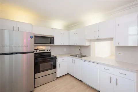 a kitchen with a sink white cabinets and stainless steel appliances