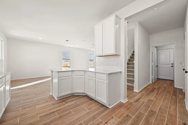 a kitchen with white cabinets and wooden floor