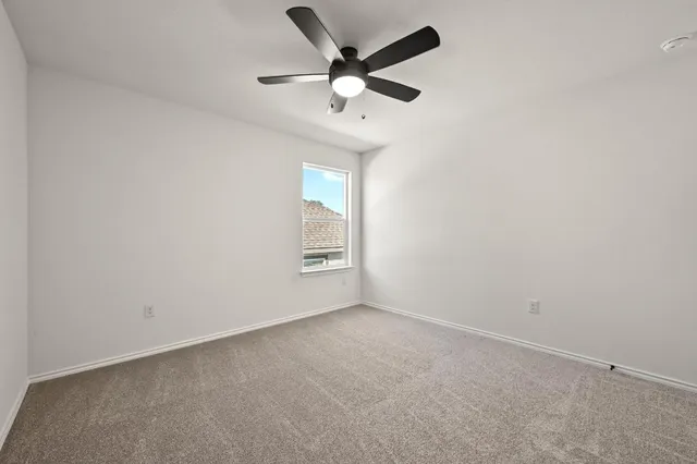 an empty room with ceiling fan and windows