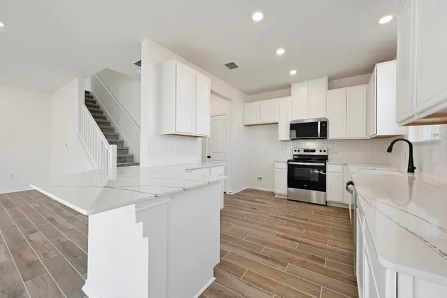 a kitchen with granite countertop a sink stainless steel appliances and white cabinets