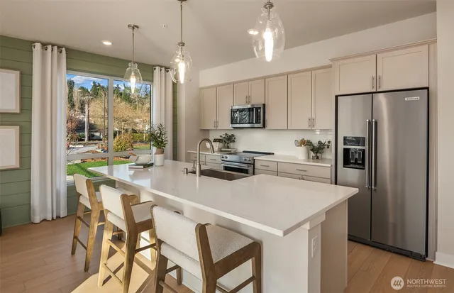 a kitchen with kitchen island a refrigerator a stove a oven a sink a dining table and chairs with wooden floor