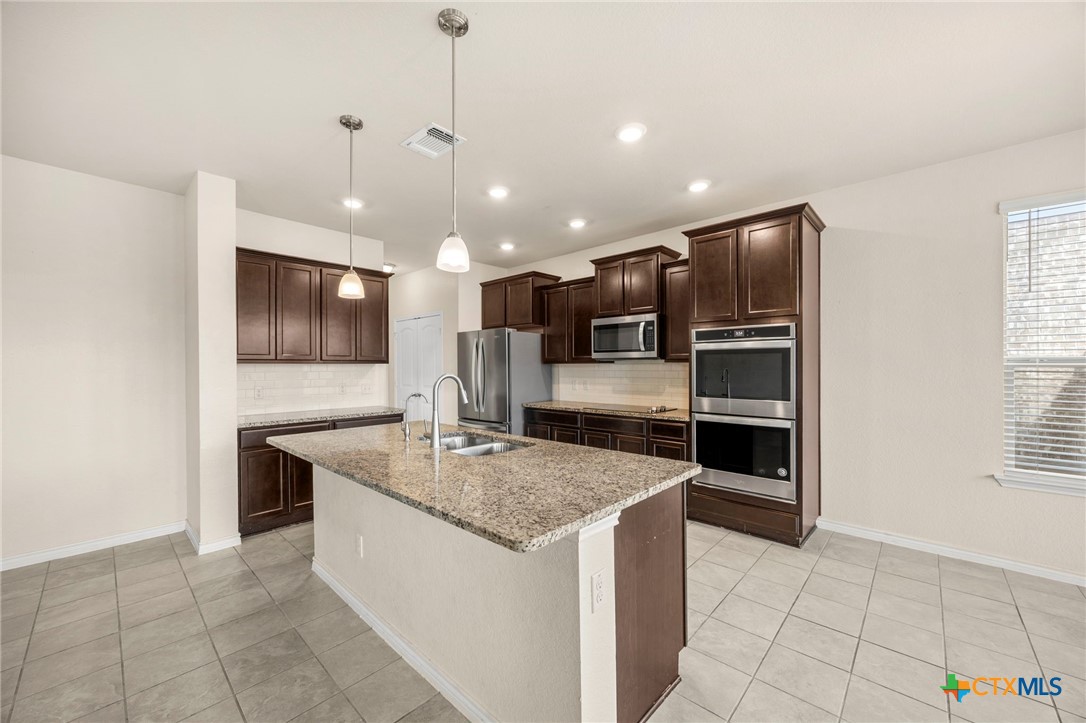 5927 Galveston Road Belton, TX 76513 - Photo 11 of 39 a kitchen with stainless steel appliances granite countertop a sink a stove a microwave and a refrigerator