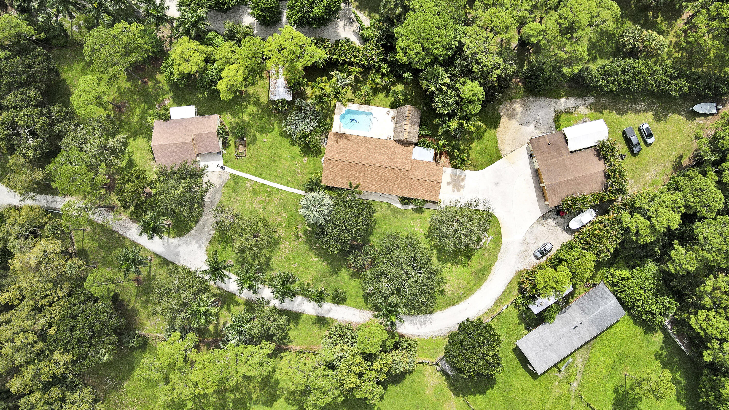 an aerial view of residential house with outdoor space and trees all around