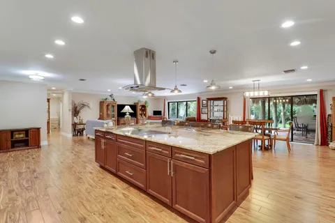 a kitchen with stainless steel appliances granite countertop a dining table chairs refrigerator and microwave