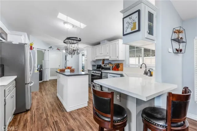 a kitchen with stainless steel appliances a sink a stove a refrigerator cabinets and a dining table