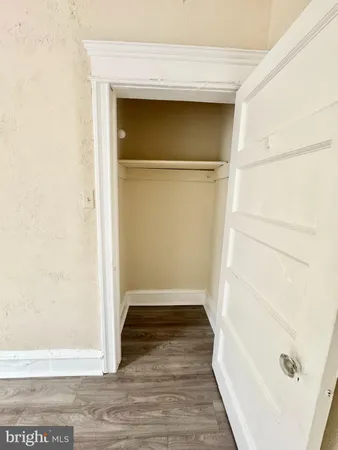 a view of an empty room with wooden floor and closet