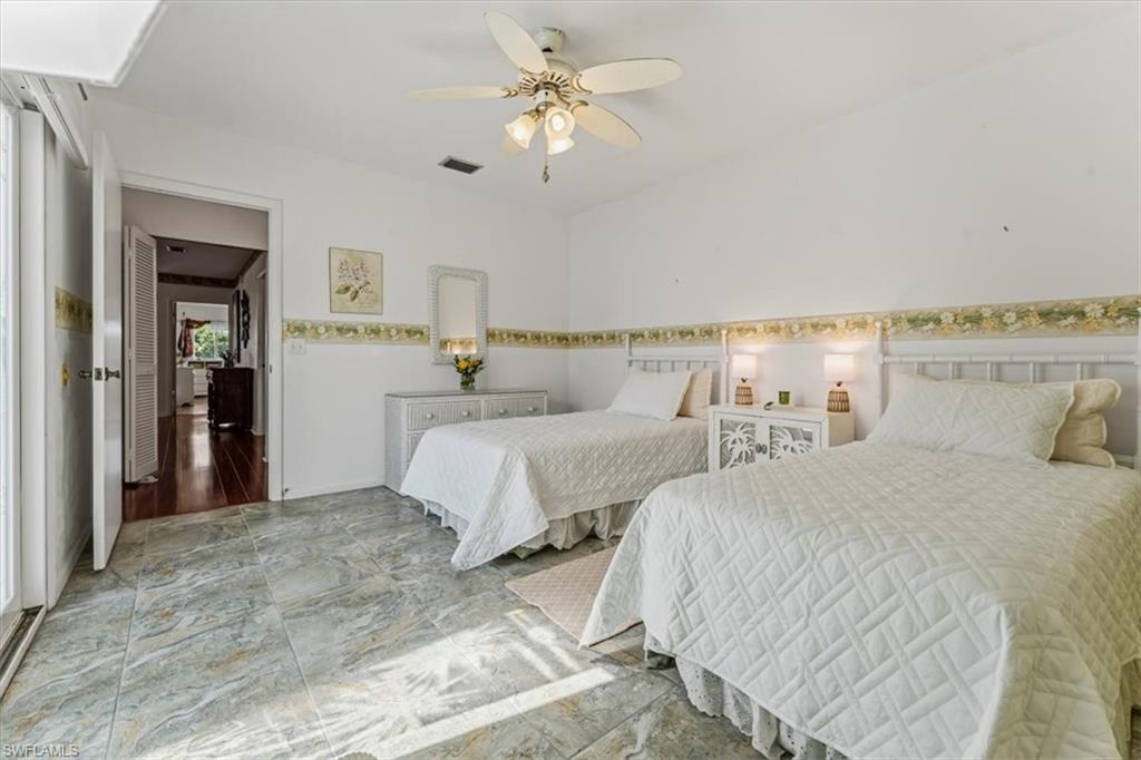 492 Bristle Cone Lane, Unit 47 Naples, FL 34113 - Photo 13 of 21 a bedroom with two large bed and a chandelier