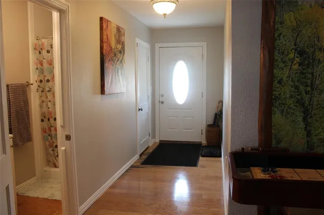 a view of a hallway with wooden floor and a bathroom