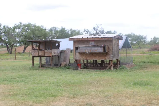a view of a field with trees in front of the house