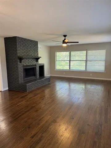 an empty room with wooden floor fireplace and windows